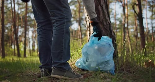 Un hombre se lleva una bolsa de plástico con basura recogida en el bosque