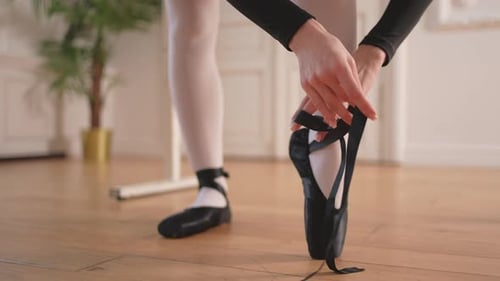 Ballerina Puts on Pointe Shoes on Leg in Dance Class Classical Ballet Dancer Woman in Dance Studio