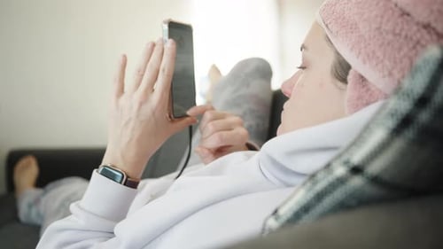 Woman Relaxing on Sofa Using a Mobile Device