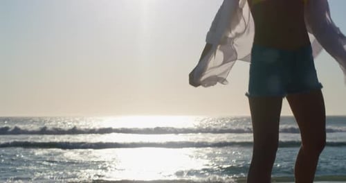 Happy, woman spinning and walking at the beach on holiday, vacation or travel in summer lens flare