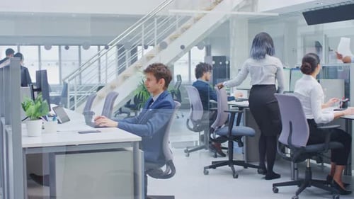 Une équipe diversifiée de chefs d'entreprise et de spécialistes travaille sur des ordinateurs de bureau avec deux rangées de tableaux