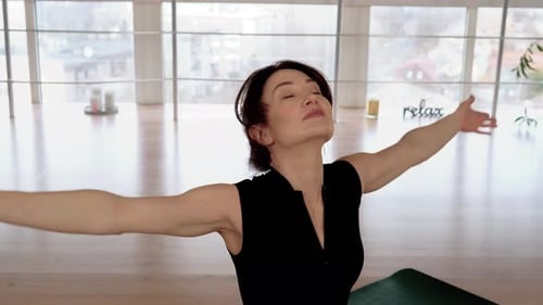 Woman Stretching Arms in Bright Yoga Studio