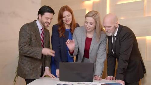 Business Team Celebrates Success Around a Laptop in Office