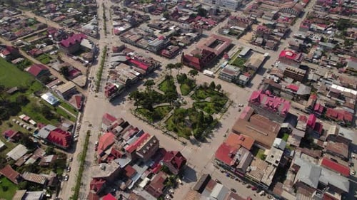 Aerial orbit drone view of a perfect green square in the middle of houses in Oxapampa, Peru.