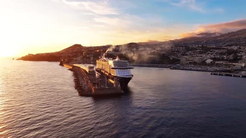 Cruise ship docking at bustling harbor during sunset in scenic coastal town