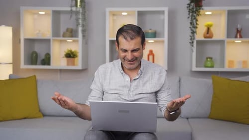 Man closing laptop with angry expression.