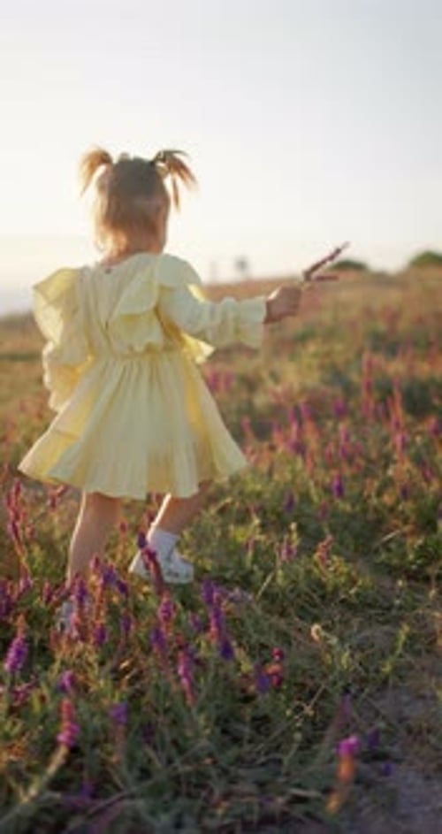 Young Girl Walks Through Field of Flowers