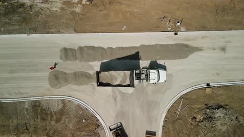 A Dump Truck Unloads Rubble for the Construction of a New Road
