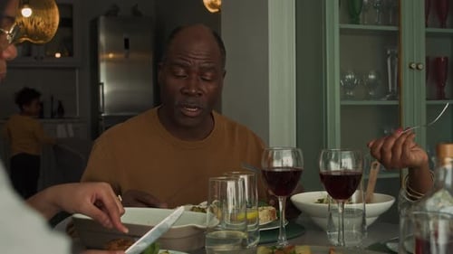 Mature African American Man Having Conversation with Family during Dinner