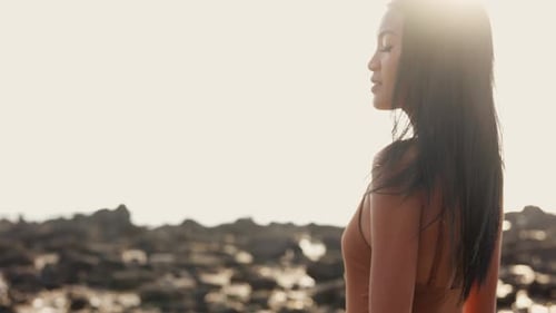 Femme en maillot de bain marron souriant sur une plage ensoleillée