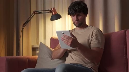 Young Adult Using Tablet on Couch at Home