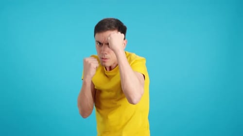 Man in Yellow Punches Fists Against Blue Backdrop