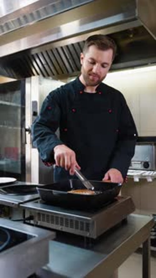 Chef masculino profesional en uniforme preparando pedidos en la cocina del restaurante.