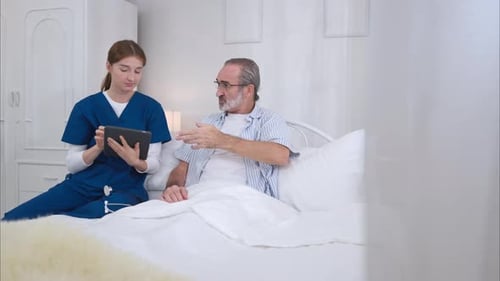 Nurse consulting with patient in hospital bed