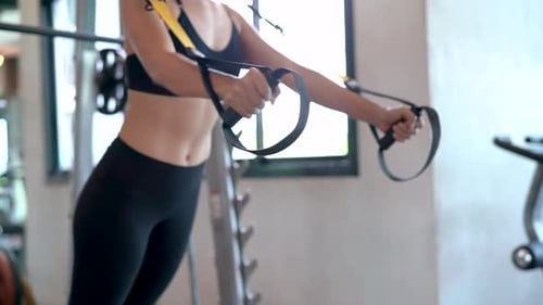 Fitness asian woman workout exercise with trx equipment in the fitness gym