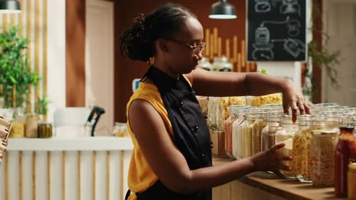 Woman Arranges Jars of Food in Shop