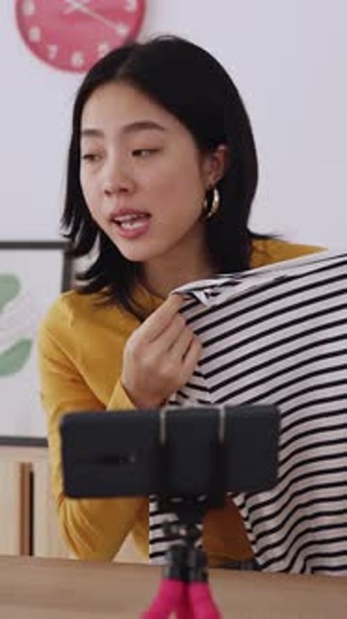 Woman Presents Striped Shirt to Camera at Home