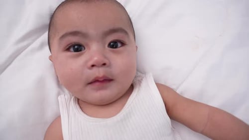 Adorable Infant Lying on White Blanket