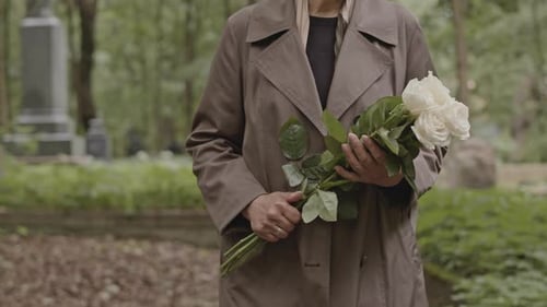 Woman with Flowers Walking on Graveyard Alley