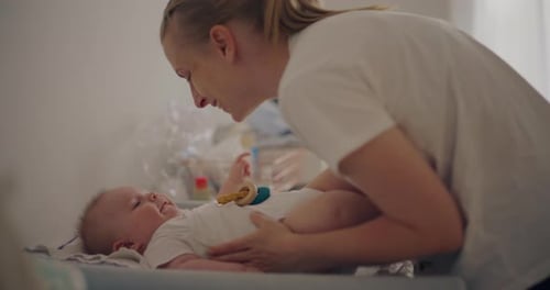 Happy Mother Hugging Newborn on Changing Table