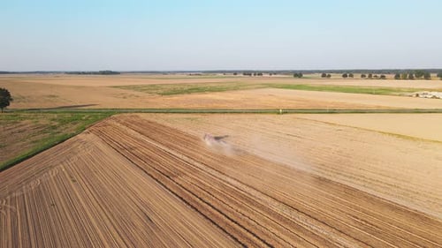Tractor Working in Agricultural Field Cultivating and Plowing Dry Soil