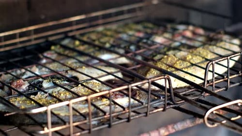 Closeup view of Galjoen on grid being barbecued on open fire. Rack focus