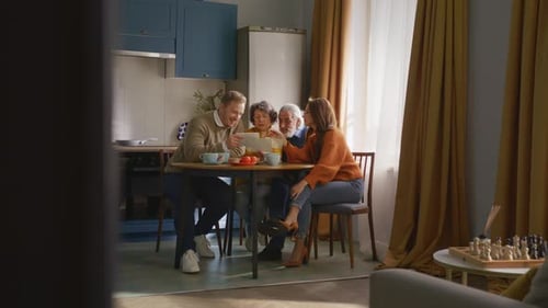 Vista lejana de personas sentadas junto a la mesa y sosteniendo un álbum
