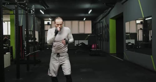 Man Training Boxing Kicks and Punches in Gym