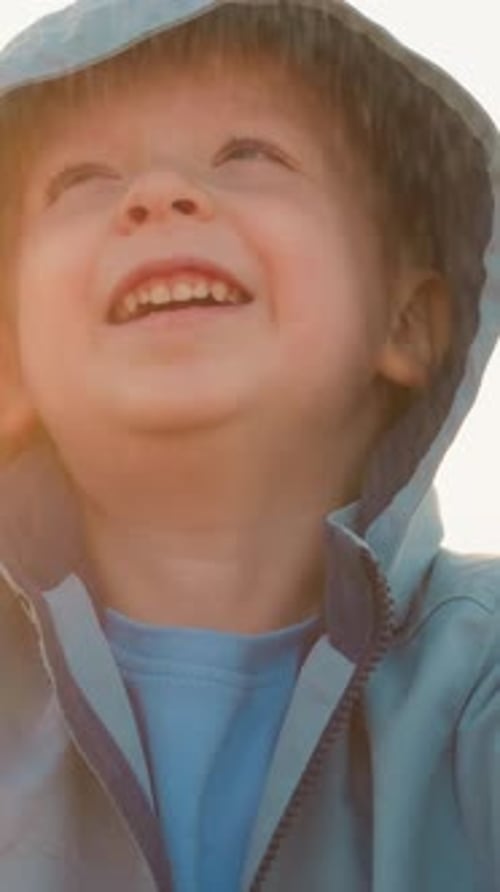 Young Boy Smiling in the Rain with a Hood
