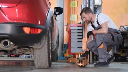 Mechanic Working on Car in Garage with Lift