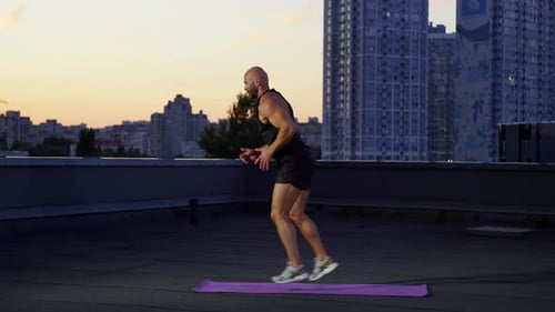 Man Doing Lunges on Rooftop During Sunset