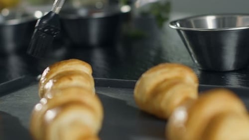Glazing Golden Croissants in Commercial Kitchen