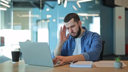 Bearded Man Working on Laptop in Modern Office