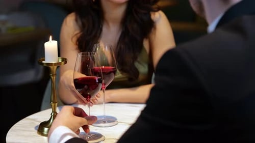 Happy Romantic Couple Sitting in the Restaurant Having Date and Holding Glasses with Red Wine