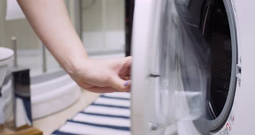 Opening the Lid and Putting Dirty Clothes to Washing in Laundry with High Key Lighting in slow mo