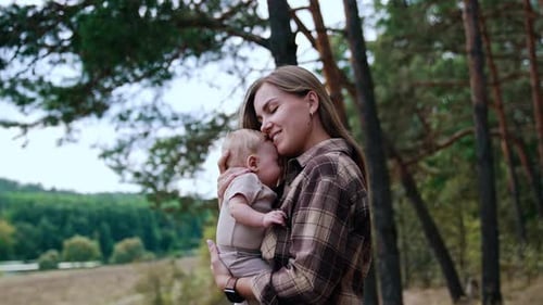 Little baby with lovely mother on hands. Pretty funny woman with newborn baby on nature.