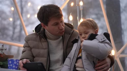 Father and Child Watching Tablet Together in Winter