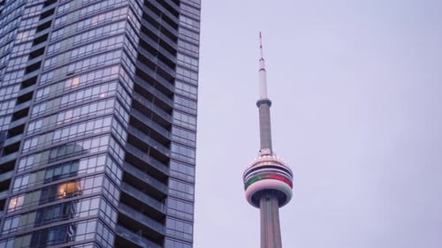 Stable, dynamic, in movement shot of CN tower in Toronto, eventually hidden by neighbouring building
