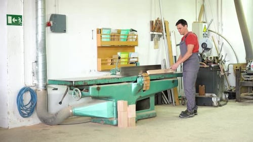 Carpenter Working at Woodworking Planer in Workshop