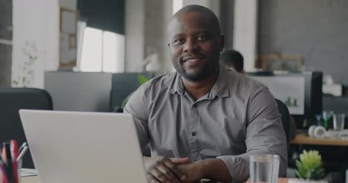 Smiling Man Sitting at Desk in Modern Office