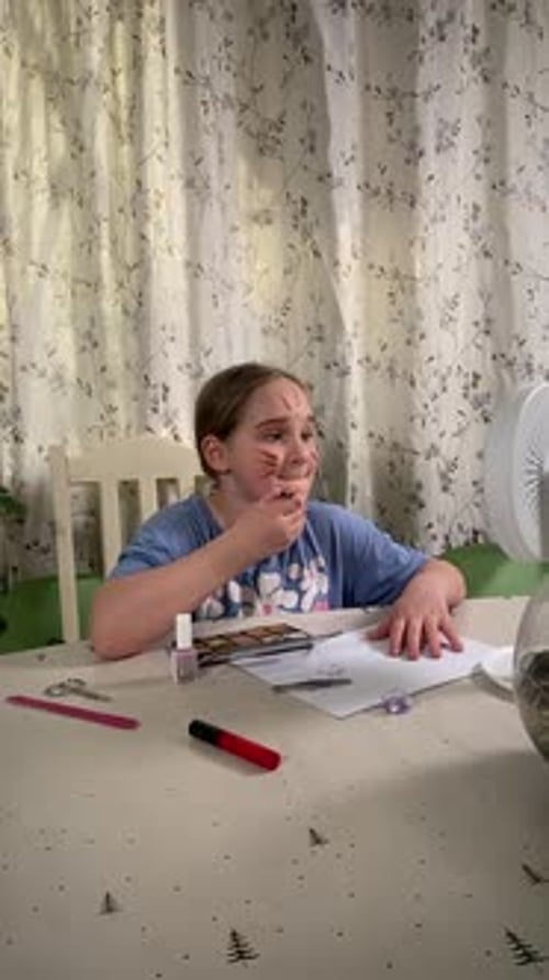 Girl Applies Theatrical Makeup at Table in Home