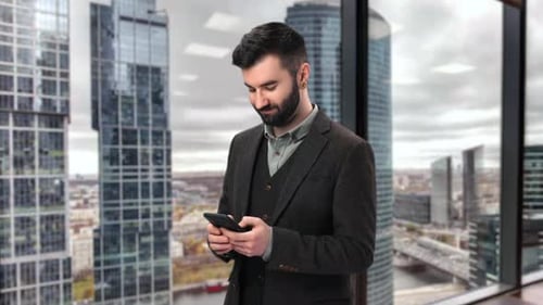Friendly Business Man Chatting Smartphone Browsing Internet at Skyscraper Tower Window Glass Office