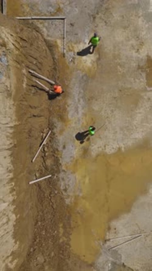 Construction Workers Digging at Muddy Urban Job Site