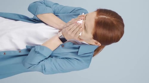 Vertical video of Woman covering mouth and nose while sneezing.