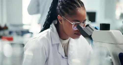 Young Scientist Analyzing Sample Under Microscope in Lab