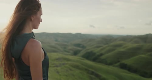 Woman Standing on Lush Green Hillside