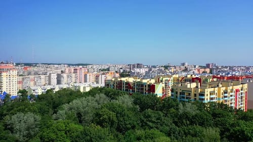 Colorful residential complex in the city. Flight over green trees on the urban background.