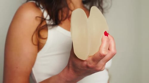 Woman Holding Silicone Breast Implants in Hand