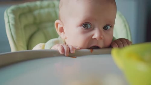 Adorable Baby Sitting in High Chair Looking Ahead