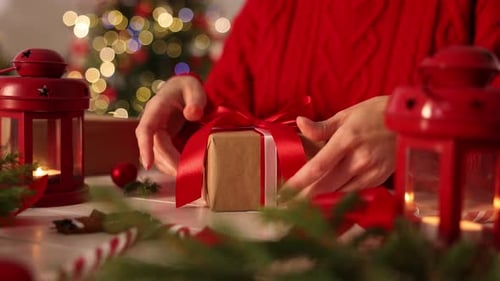 Woman Tying Red Ribbon on Christmas Present